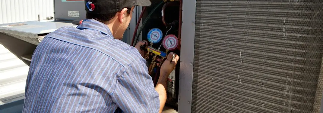 HVAC technician servicing a condenser unit in Urbana